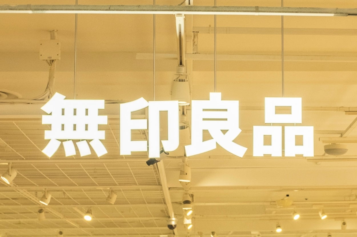 People shopping at a well-lit Muji store, featuring organized shelves displaying various home and lifestyle products
