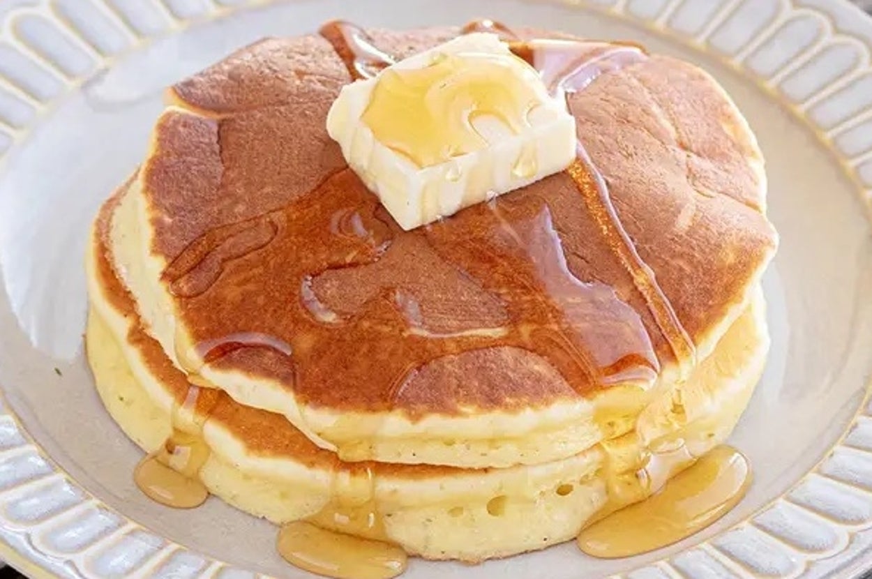 パンケーキ2枚にバター1個とメープルシロップがかかった朝食の皿。