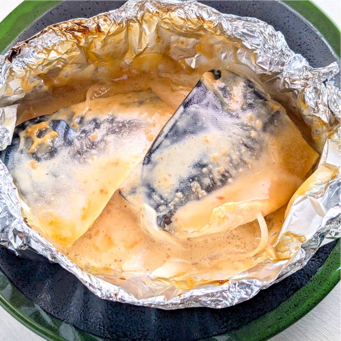 アルミホイルに包まれた焼き魚の様子。ソースがかかっており、料理が完了している様子が見える。