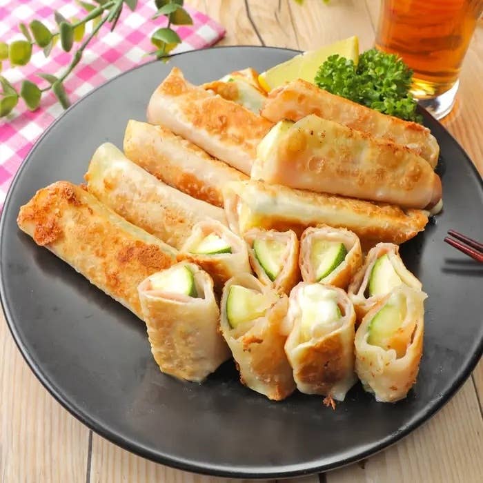 お皿に盛られた春巻き風の料理があり、チーズと野菜が巻かれている。横にレモンとパセリが添えられている。