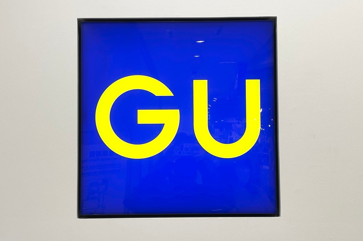 A bright sign with large yellow letters "GU" on a blue background