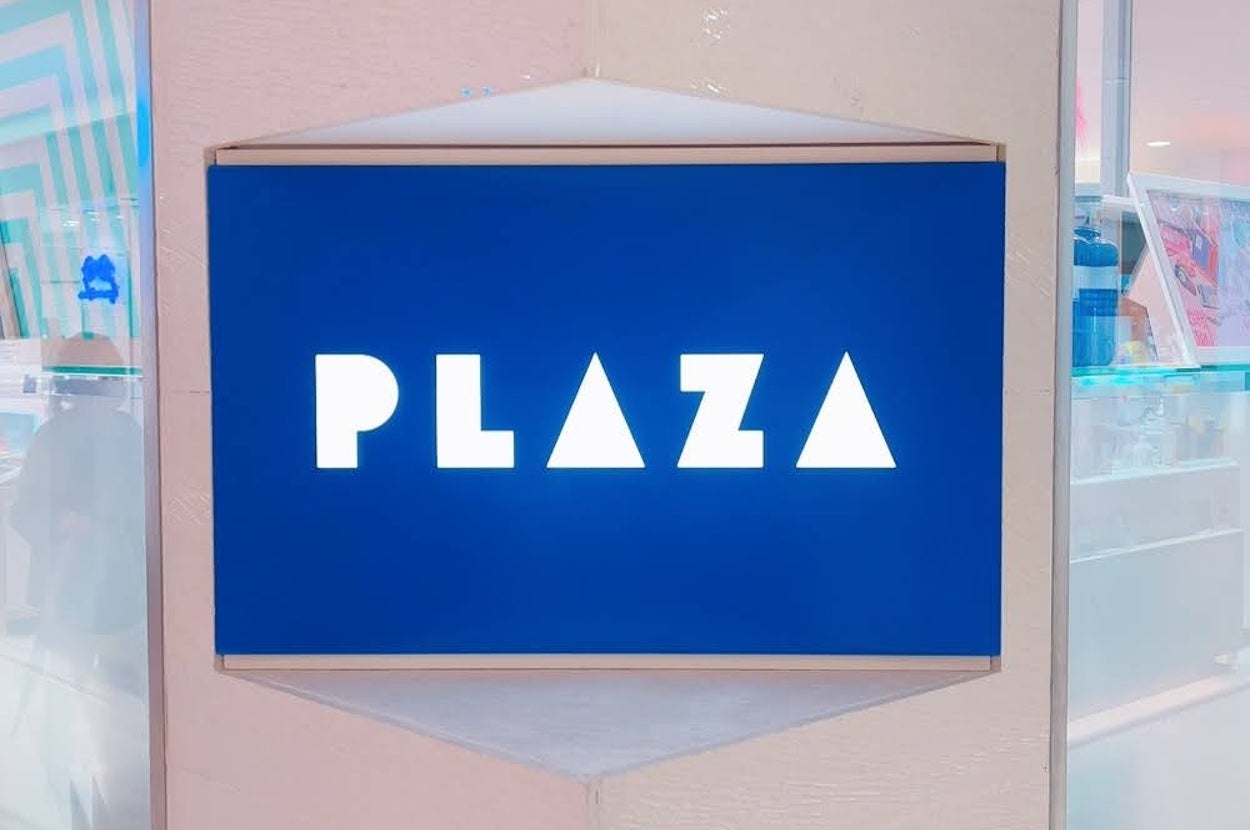 青地に「PLAZA」と書かれた看板が壁にかけられている。