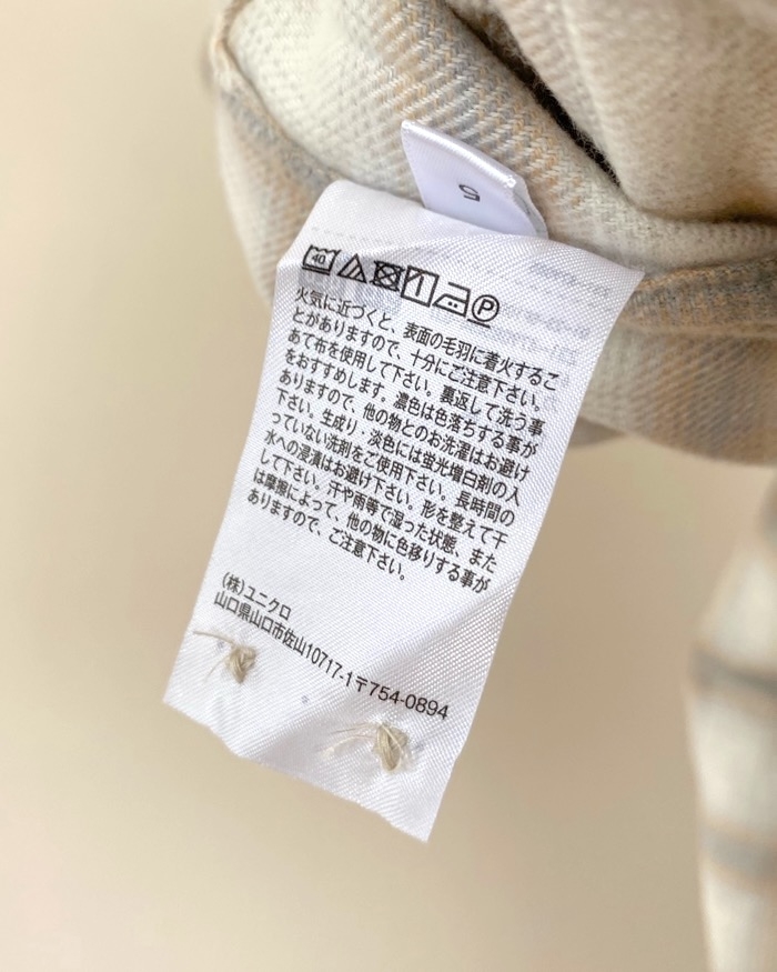 Clothing care label with instructions in Japanese. Symbols indicate washing, drying, and ironing guidelines. Brand mentioned: Uniqlo