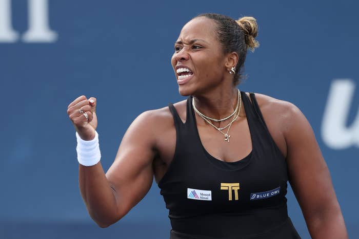 Tennis player fist-pumps during a match, wearing a sleeveless athletic outfit