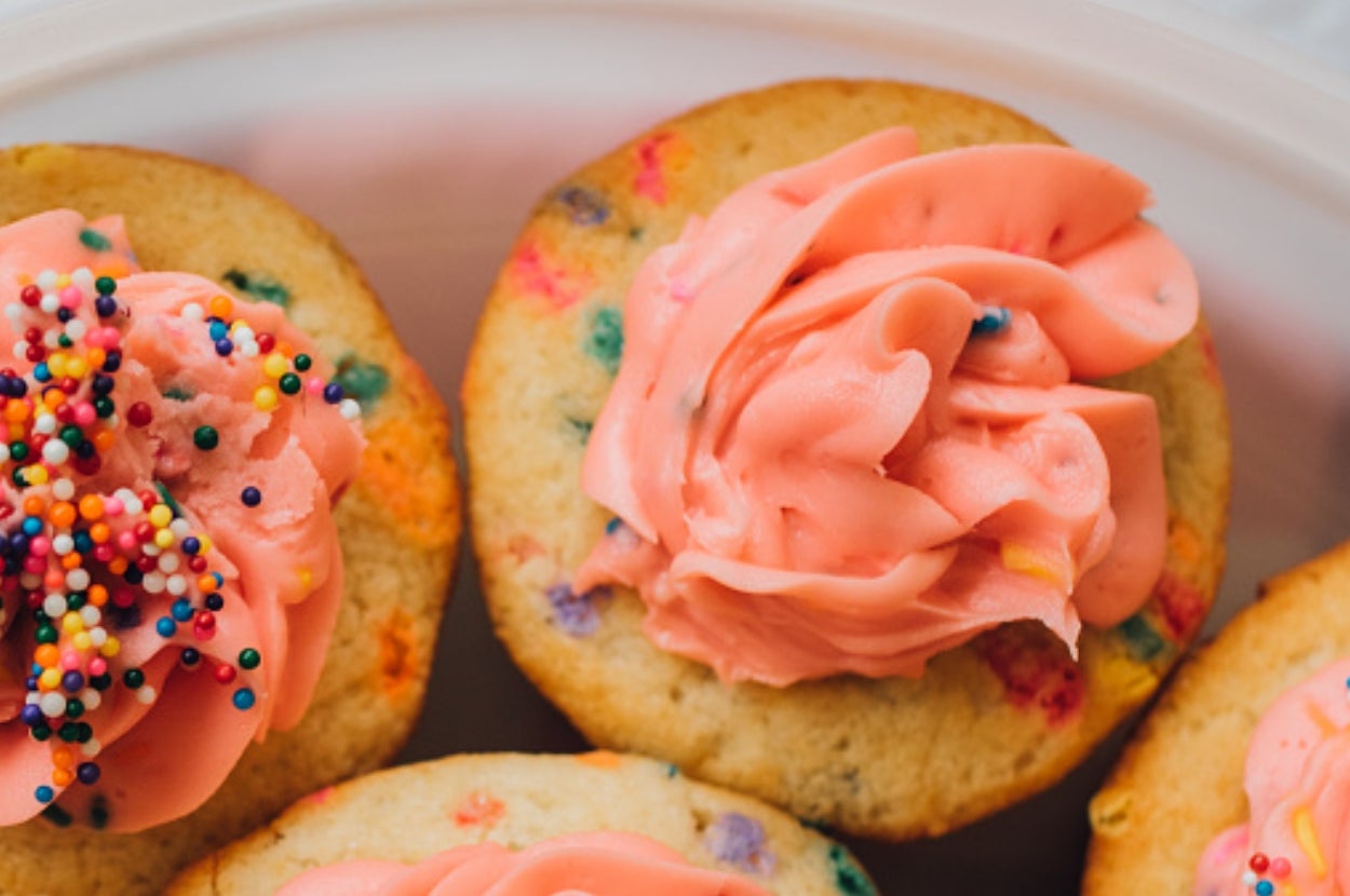 Cupcakes with colorful sprinkles and pink frosting swirls on a plate