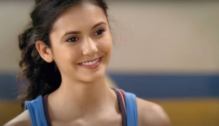 Person smiling successful a casual setting, wearing a sleeveless top, looking blessed and relaxed