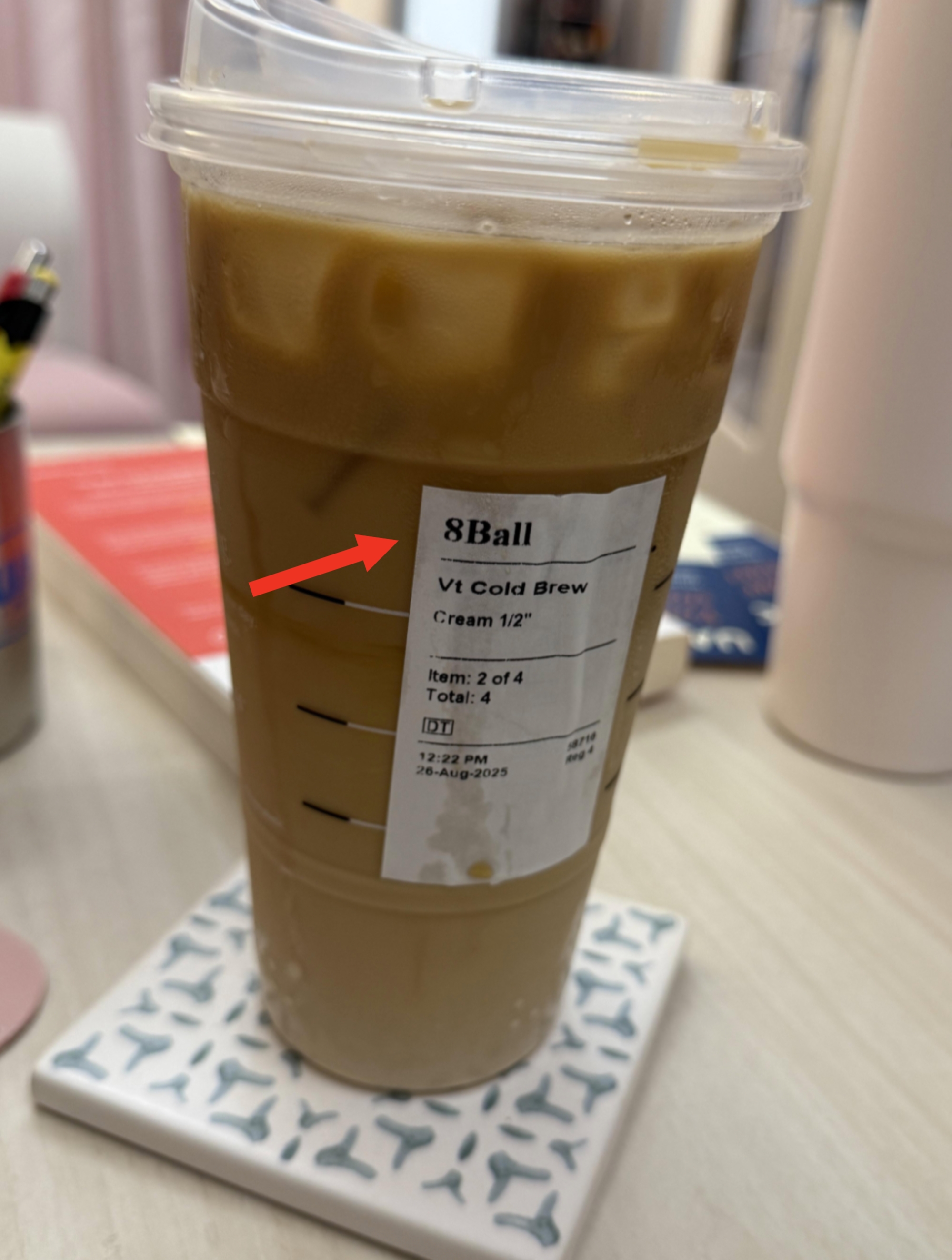 Iced java  successful  a wide   cupful  with a statement   showing bid   details, placed connected  a coaster connected  a desk