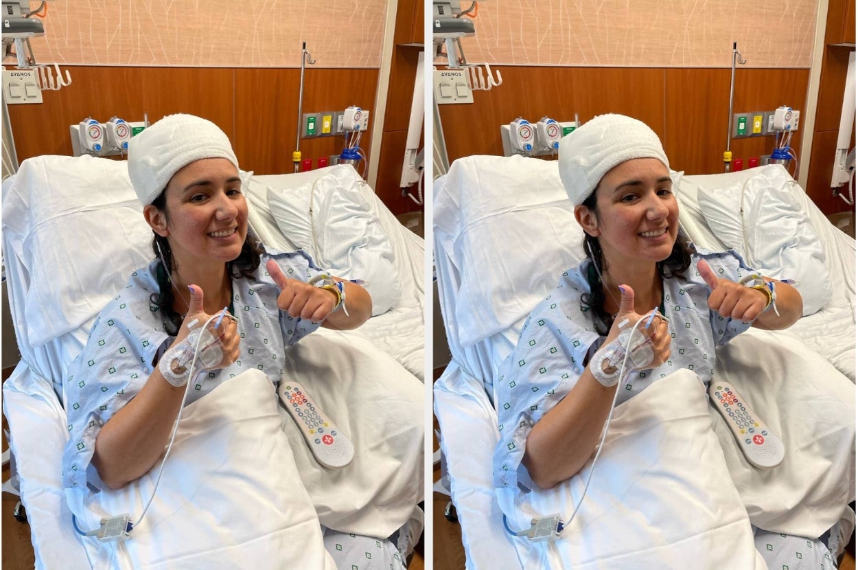 Person in a hospital bed, wearing a gown and bandage on their head, smiles and gives a thumbs-up, conveying a positive and resilient attitude