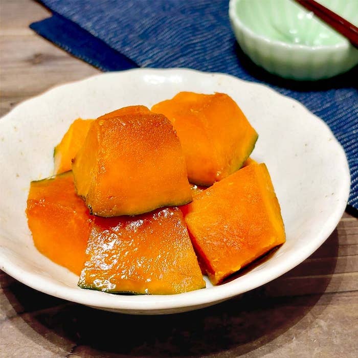 皿に盛られた煮物のカボチャ。家庭的な料理の一品としてテーブルに置かれている。