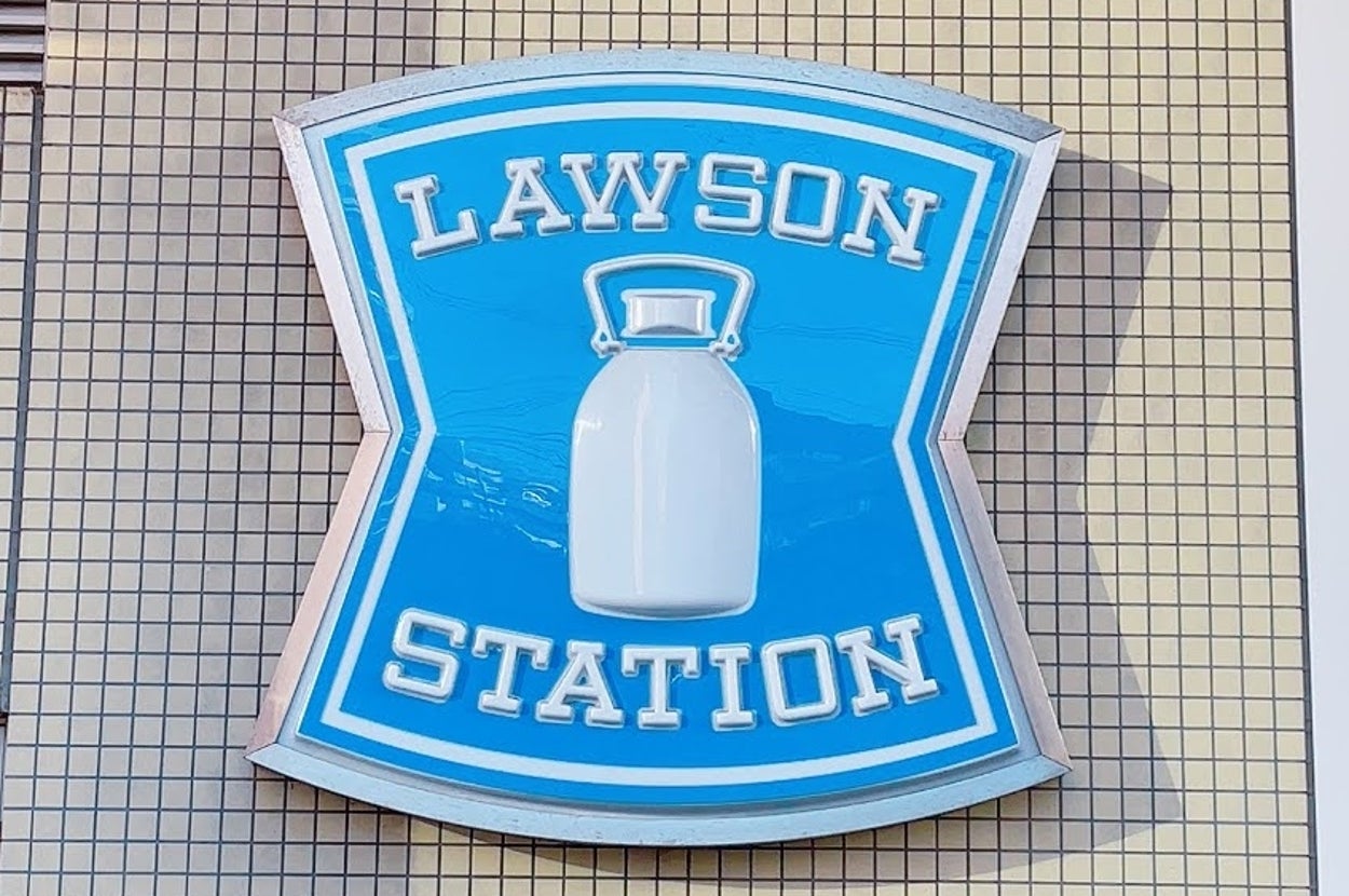 青地にミルク缶のイラストが描かれた「LAWSON STATION」の看板。店舗外壁に掲げられている。