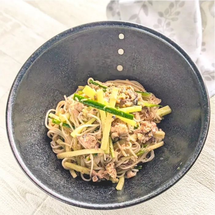 シンプルな器に盛られたそばと野菜の料理。細切りのズッキーニとハーブがトッピングされている。