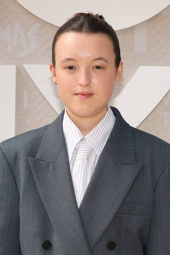 Person successful ceremonial striped suit and necktie stands connected a reddish carpet backdrop. Hair is neatly tied back