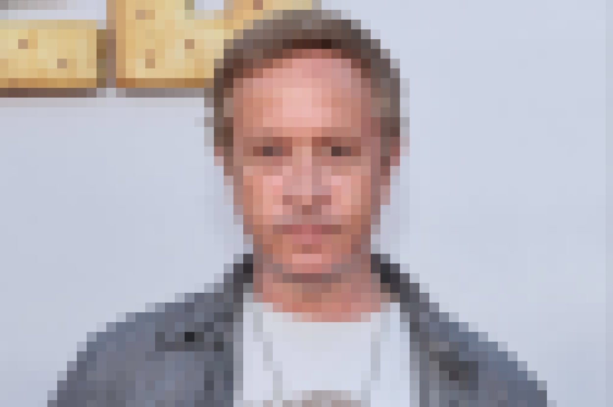 Man in a casual shirt and graphic tee poses at an event