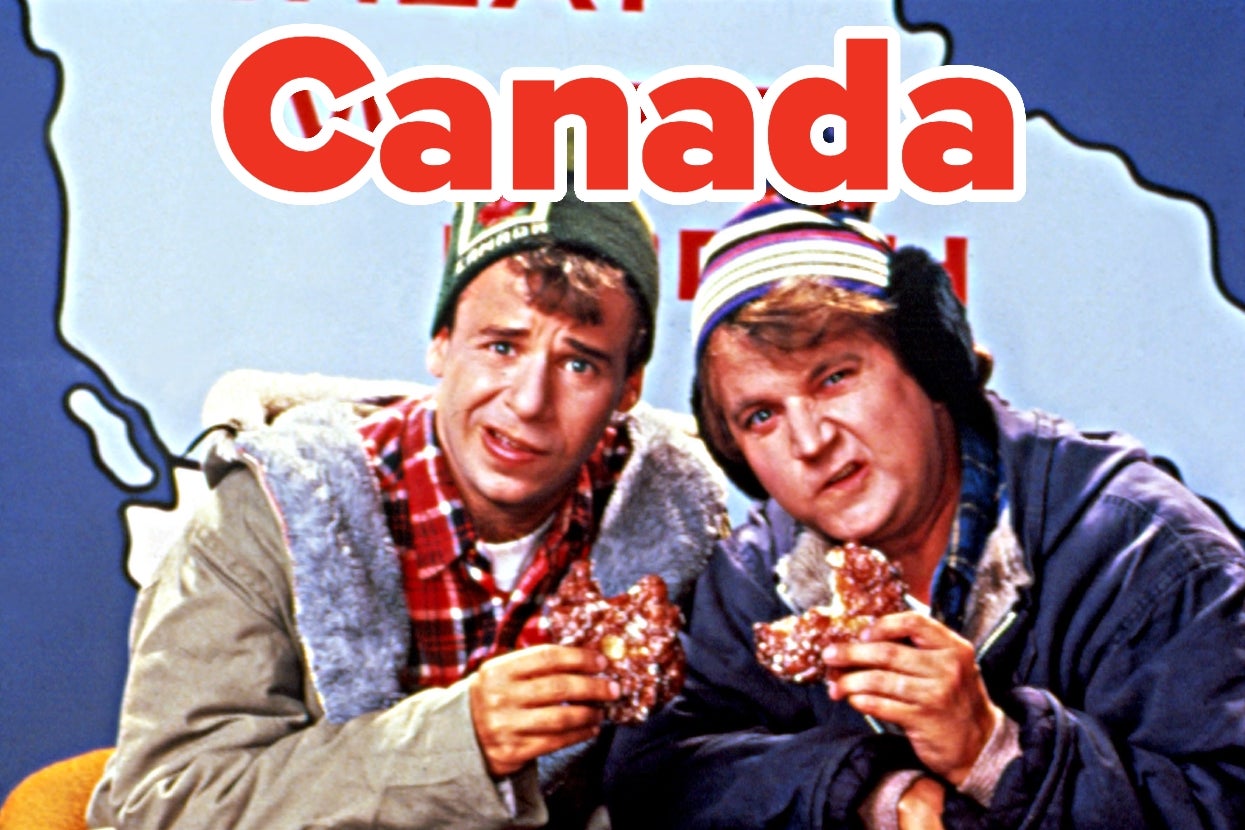 Rick Moranis and Dave Thomas as Bob and Doug McKenzie in "Strange Brew" wearing winter clothing holding food, posing humorously in front of a "Canada" sign