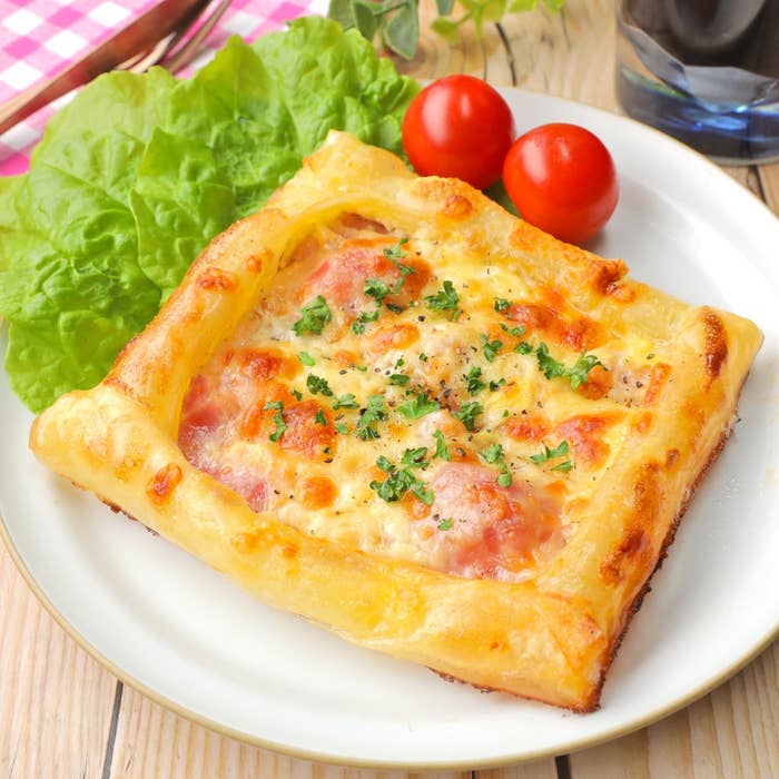 四角いピザ風パイとサラダとトマトのプレート、木製テーブルに配置。