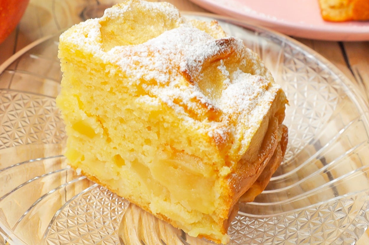 皿に盛られた焼き菓子の一切れ。糖の粉が上に軽く振りかけられている。背景に立派な焼き菓子全体が見える。