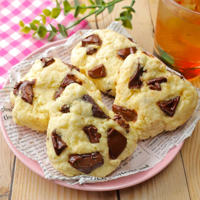 チョコレートチャンクが入った焼き菓子が新聞紙風のペーパーに乗せられて、プレートに盛られている。隣に飲み物がある。