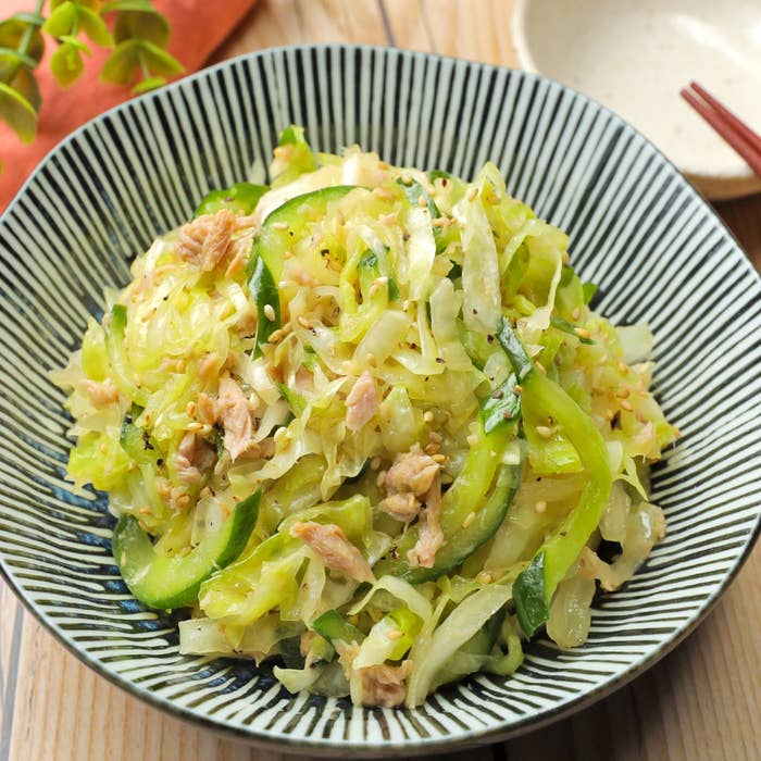 キャベツとキュウリのサラダが美しく盛り付けられた皿。シュレッドチキンとゴマがトッピング。