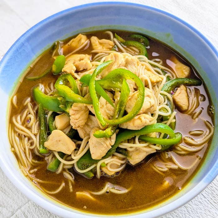 麺の入ったスープボウル。上に鶏肉と緑のピーマンがのっています。