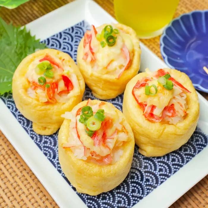 皿に盛られた4つのいなり寿司にねぎとカニ風味かまぼこをトッピングされています。