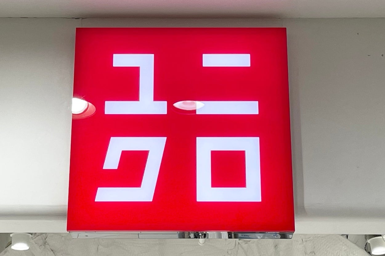 A red Uniqlo store sign with white Japanese characters and logo, displayed above an entrance
