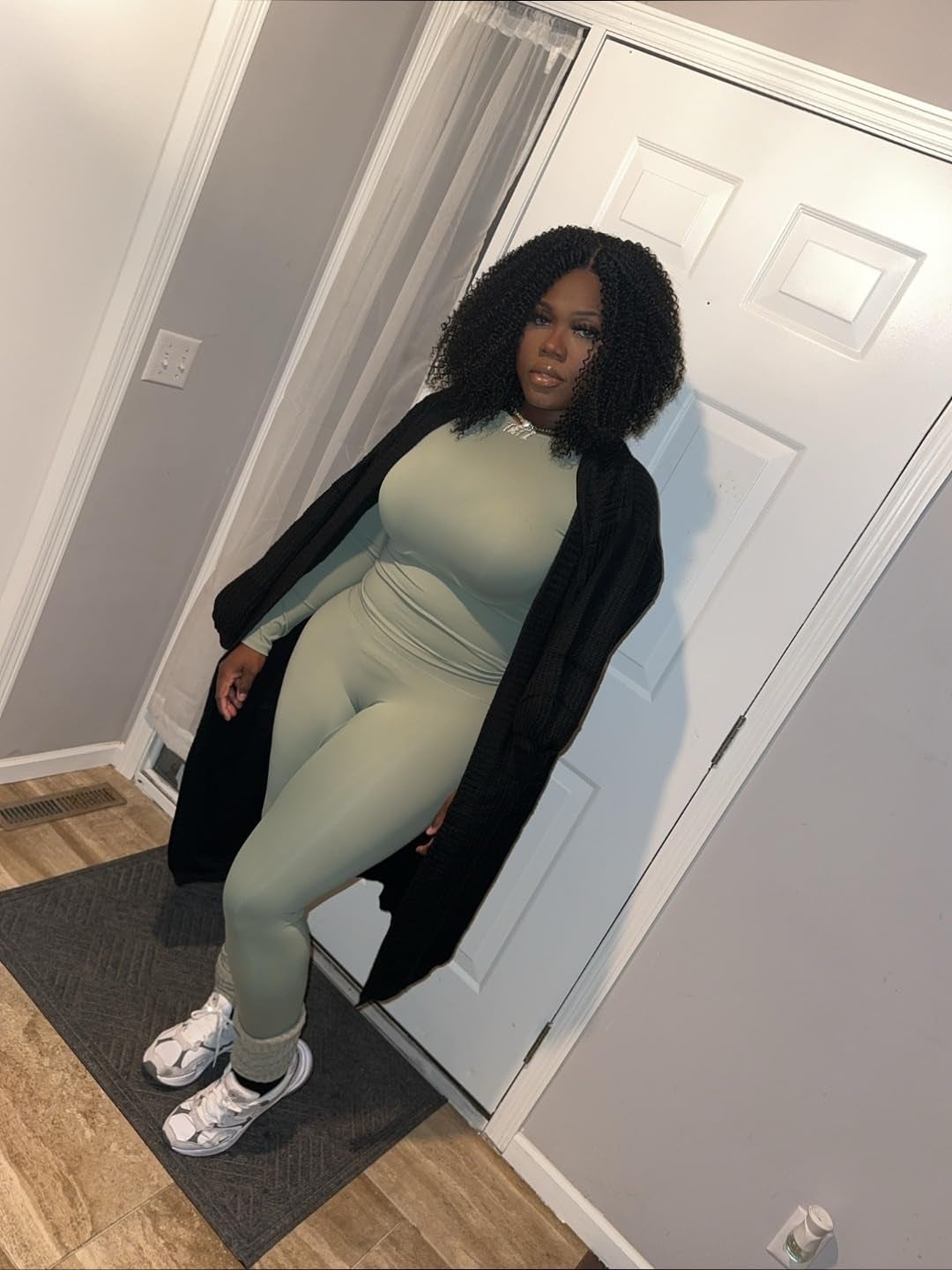Person successful  a fitted outfit with a robe-style overgarment   and sneakers, posing indoors