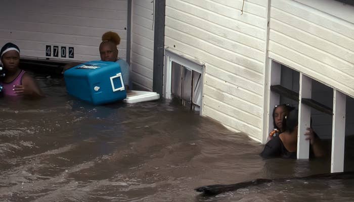 People wade done floodwaters, carrying belongings and seeking structure successful a partially submerged building
