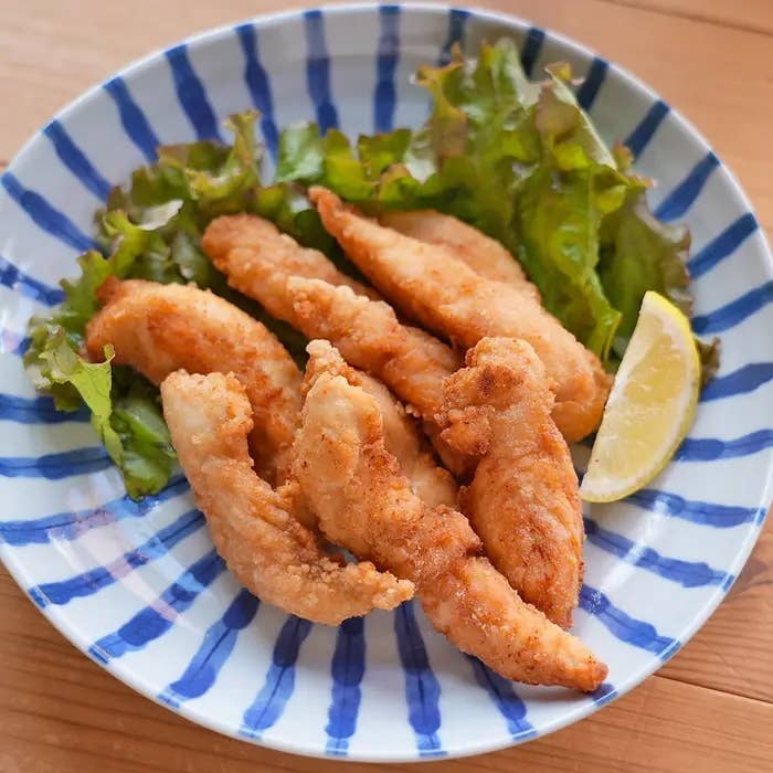 皿に盛り付けられたささみのスティック唐揚げ。レタス、レモンのくし切りが添えられている。