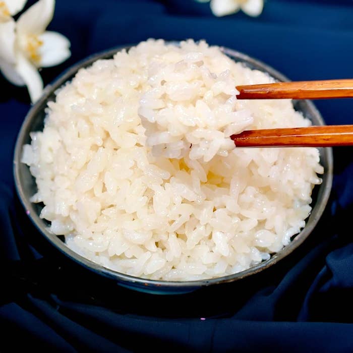 ボウルに盛られた炊きたてのご飯を箸でつまんでいる様子。