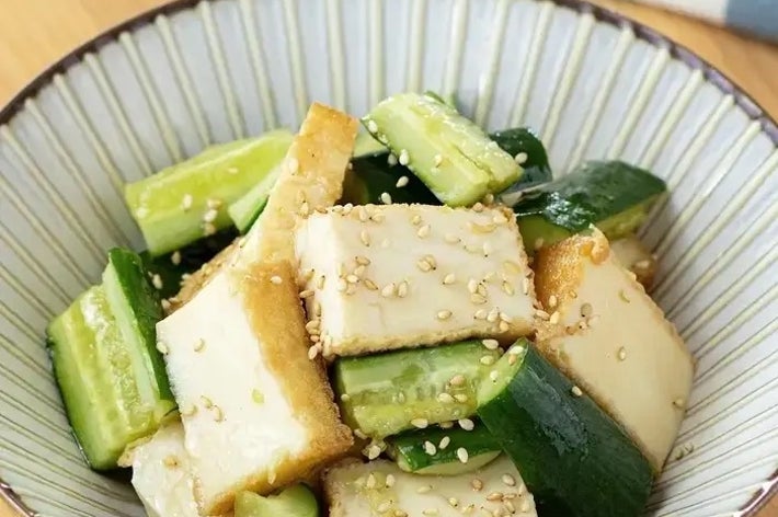 豆腐ときゅうりのサラダ。ゴマがトッピングされており、健康的でさっぱりした料理です。