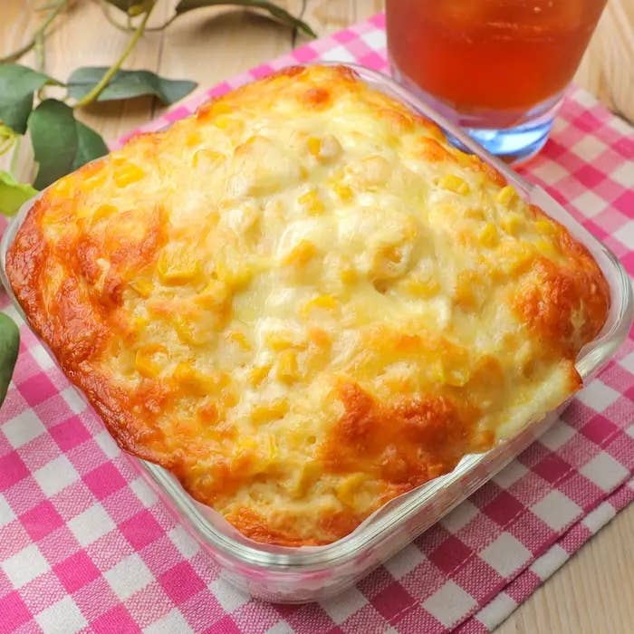 ガラス容器に入った焼きたてのコーンパン。隣にアイスティー。ピンクのチェック柄のナプキンが敷かれています。