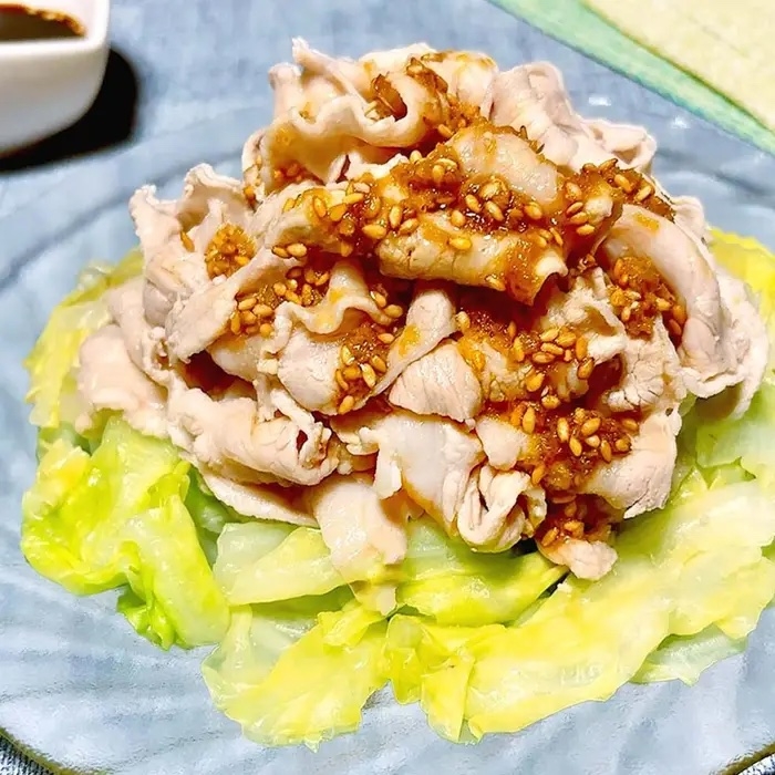 茹でた薄切り豚肉がキャベツの上に盛られ、ごまソースがかかっている料理。