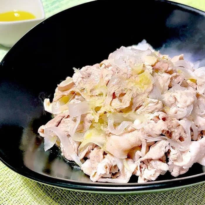黒い器に盛られた冷しゃぶサラダ。薄切りの豚肉と薄切りの玉ねぎがトッピングされている。