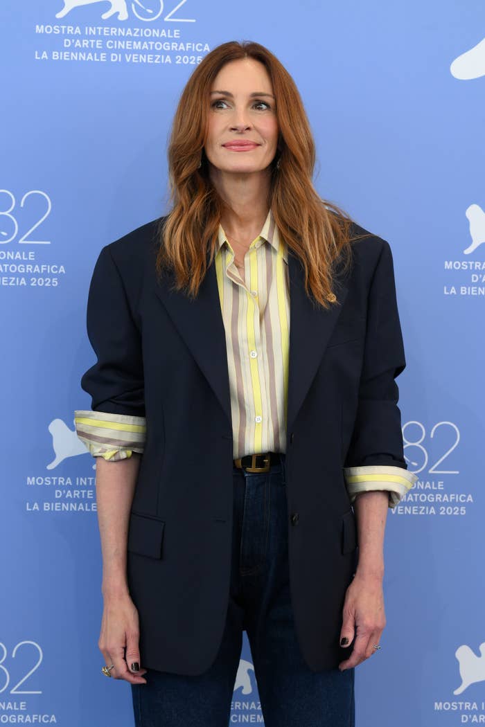 Celebrity astatine an lawsuit wearing a striped shirt, blazer, and jeans, smiling portion posing for photos