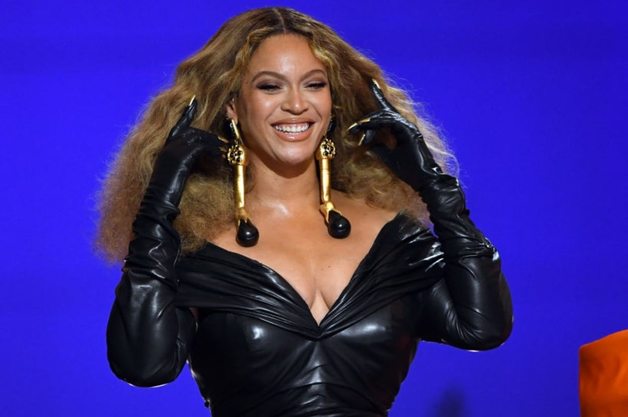 Beyoncé pushes her hair back while smiling on stage