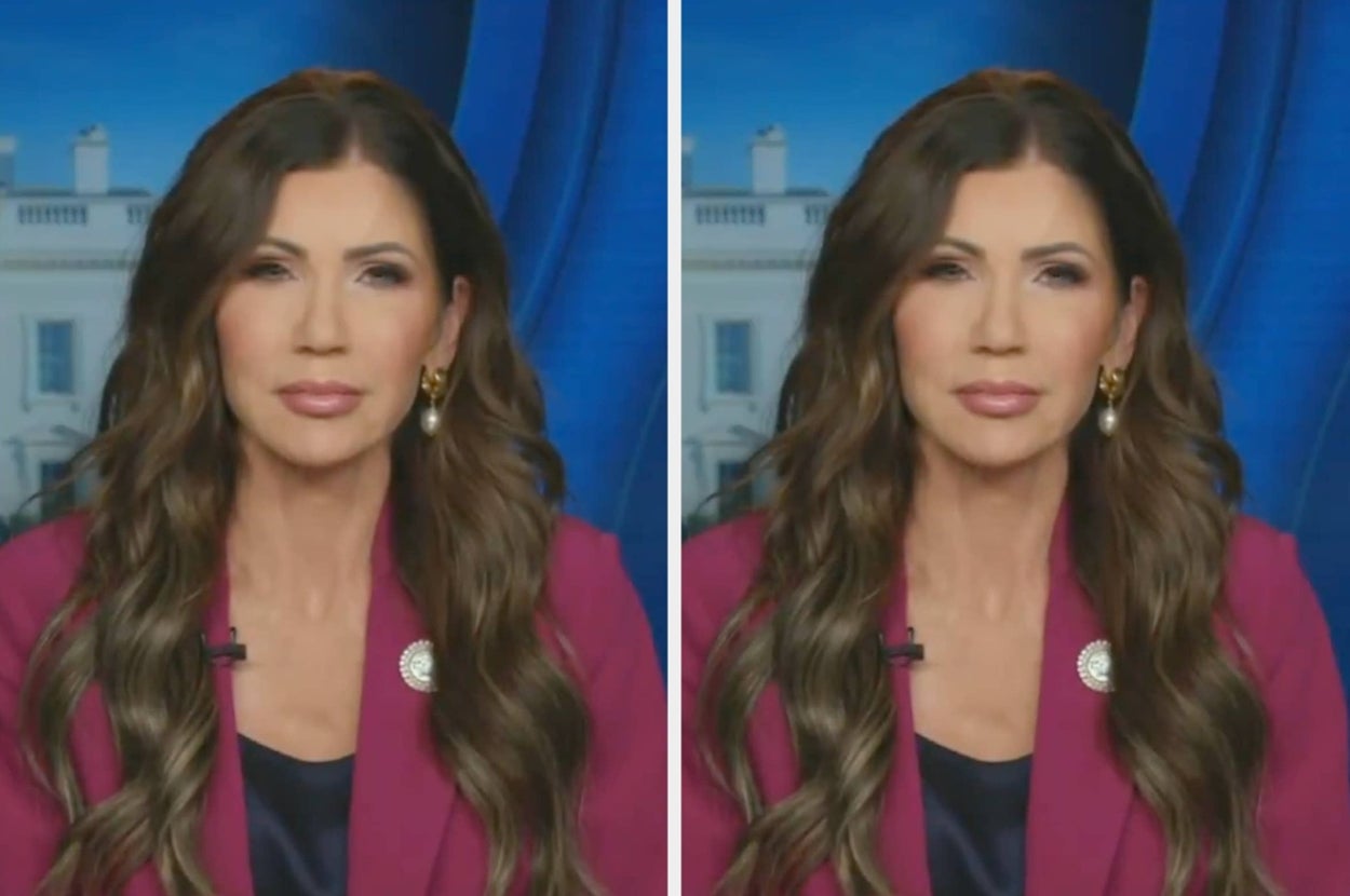 A woman with long wavy hair, wearing a formal blazer and statement earrings, appears in front of a blurred architectural backdrop