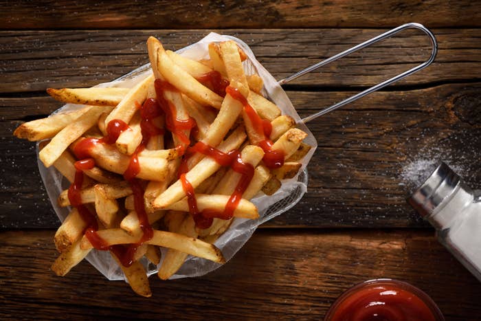 Fries successful a handbasket topped with ketchup, placed connected a woody array adjacent to a brackish shaker