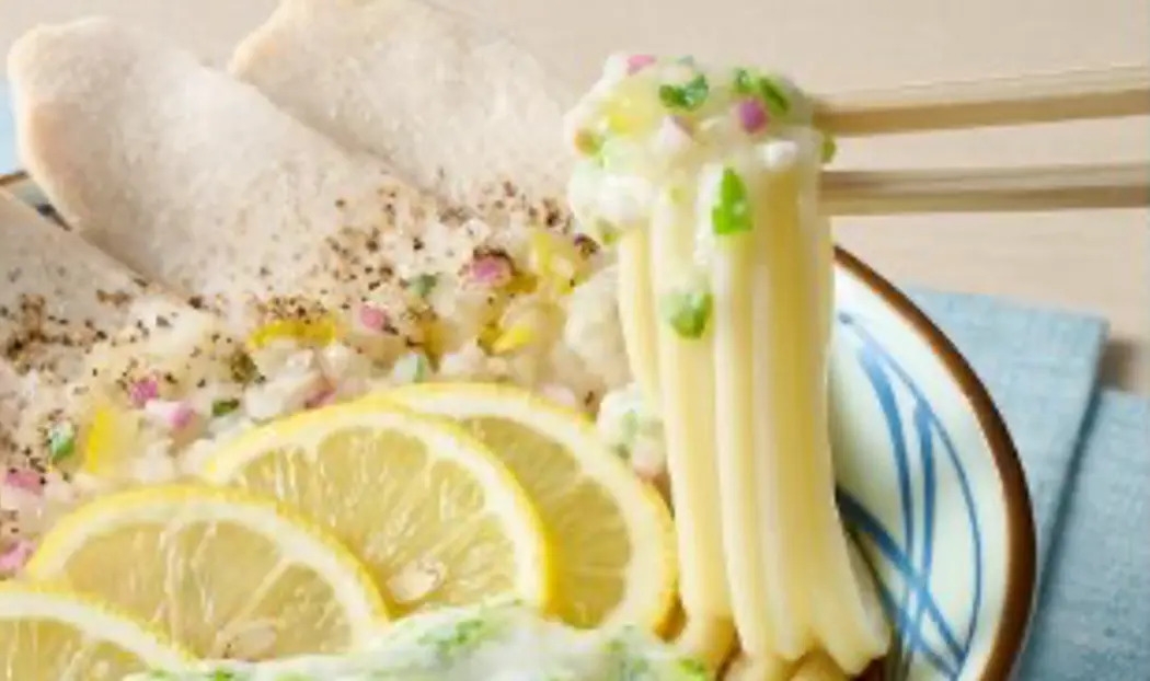 「柑橘香る ねばとろ鶏ぶっかけうどん」を持ち上げている画像/「丸亀製麺」のプレスリリースより