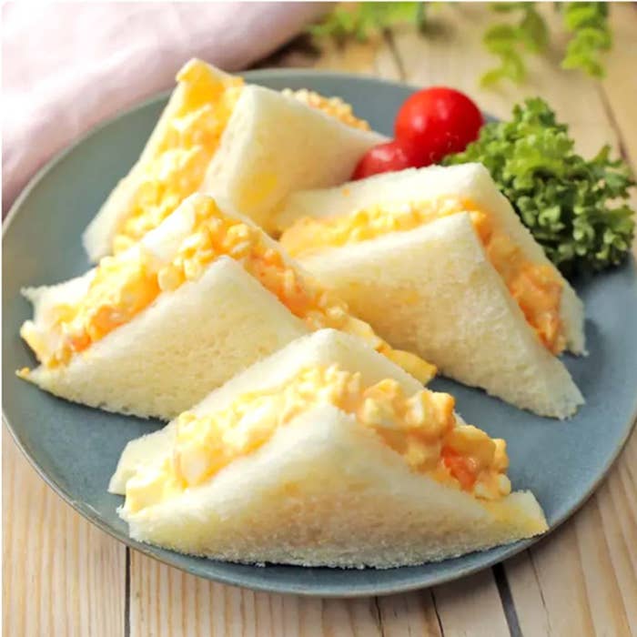 皿に盛られた卵サンドイッチ。トマトが付け合わせで添えられています。