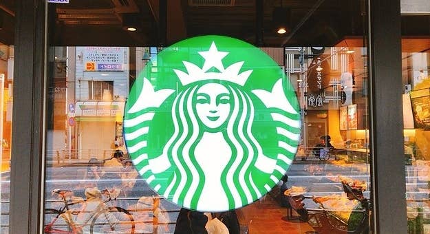 スターバックスの店舗正面にある大きなロゴ。背景には通行人や自転車が映る市街地の風景。