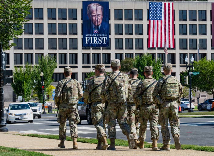 Soldiers successful azygous locomotion toward a gathering with a ample banner of a nationalist fig and an American flag