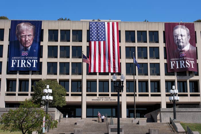 Banners of Donald Trump and Mike Pence with "American Workers First" substance bent extracurricular a authorities gathering with a ample U.S. flag