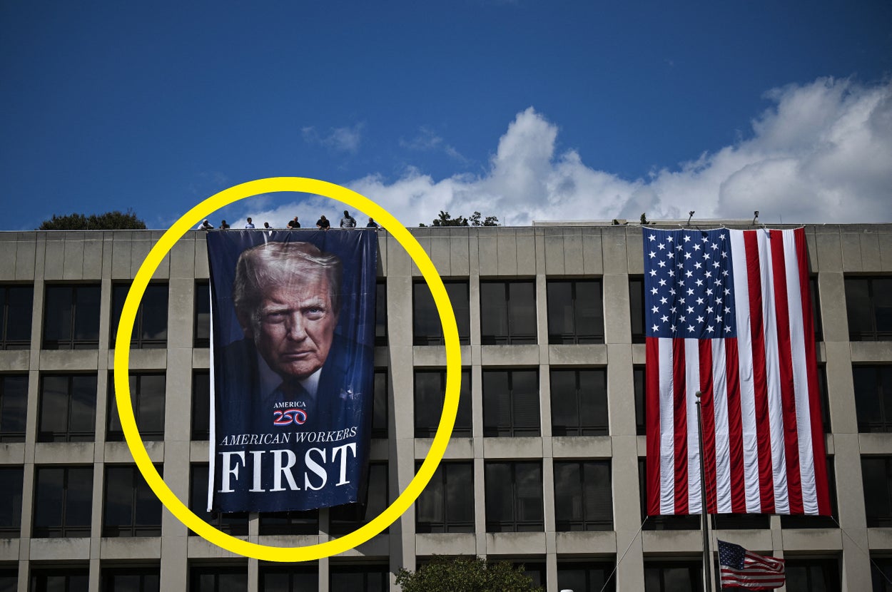 Building with a large banner of a man with text "American Workers First" and an American flag next to it. People are visible on the roof