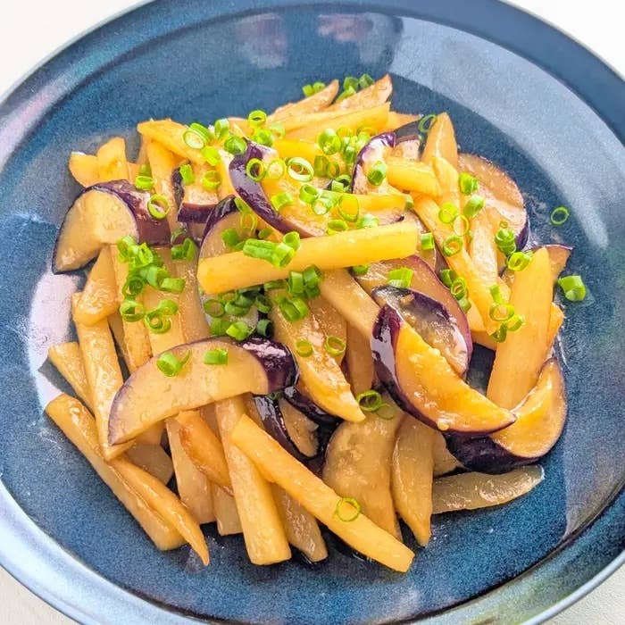 皿に盛られたじゃがいもとナスの炒め物、上に小ネギがトッピングされています。
