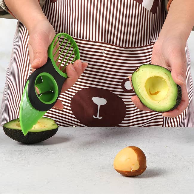 Person utilizing an avocado slicer to chopped and pit an avocado connected a room counter