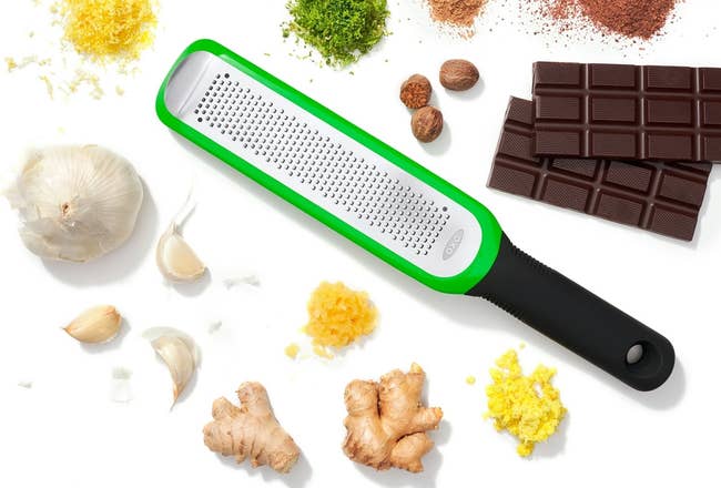 Grater with grip surrounded by spices, chocolate, garlic, and ginger, showcasing room essentials for enhancing flavors successful cooking