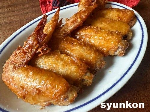 お皿に乗った香ばしく揚げた手羽先。左下に「syunkon」の文字。