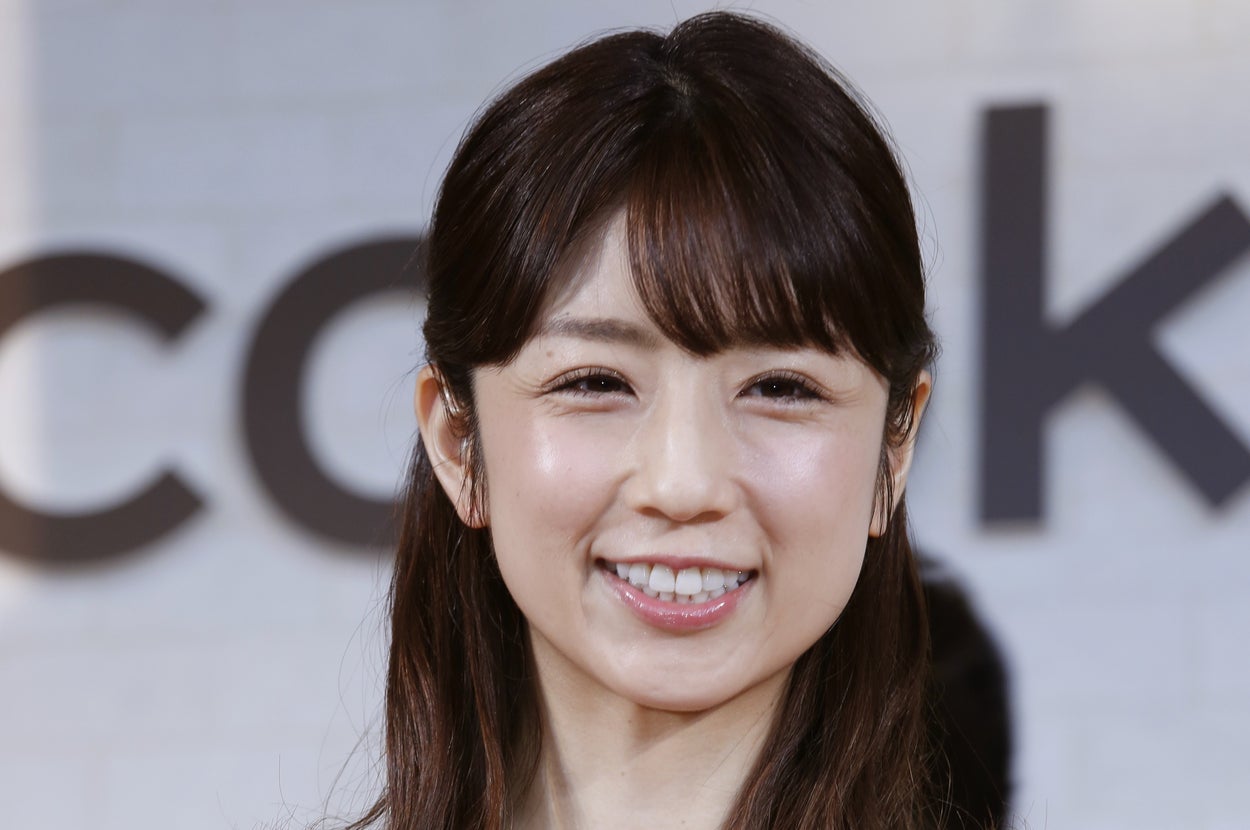 女性が花柄のドレスを着て微笑んでいる。背景にイベント会場の雰囲気が感じられる。