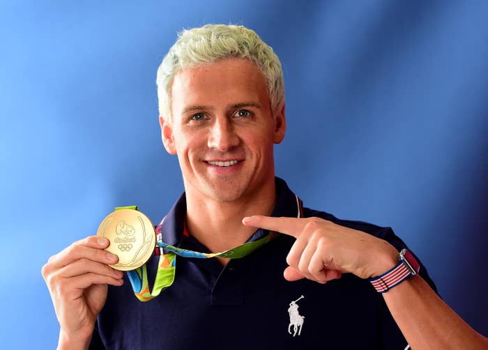 Athlete with blond hairsbreadth holds an Olympic golden medal, wearing a casual polo garment with a equine emblem