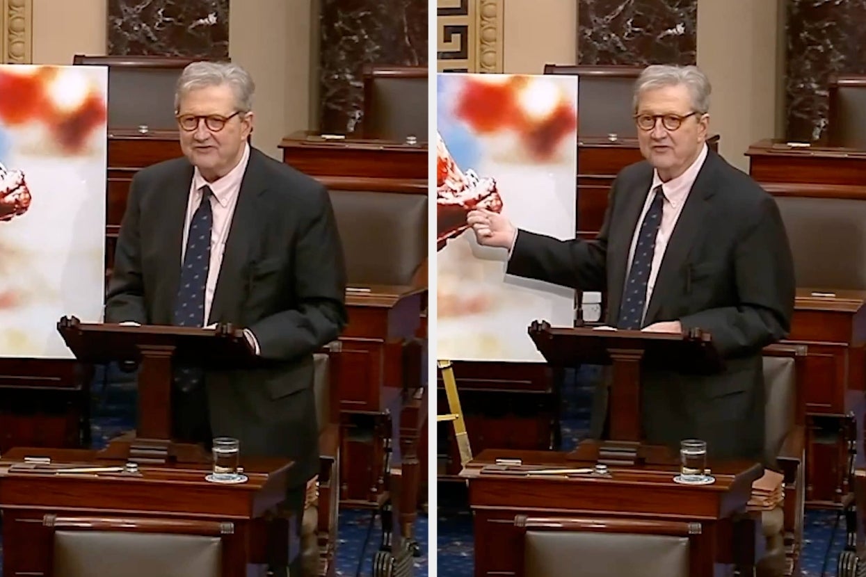 Man in suit stands at podium in formal setting, gesturing toward a large image of fried chicken